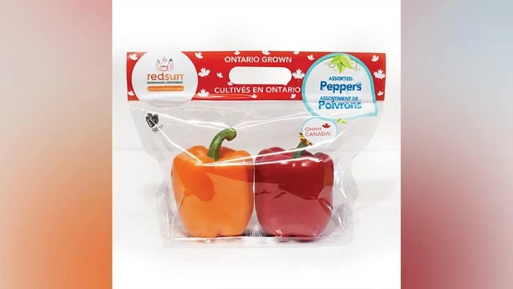 A plastic bag containing one orange pepper and one red pepper.