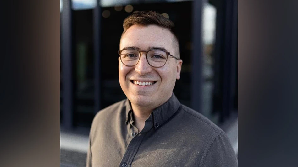 Man with glasses and gray shirt smiling for headshot