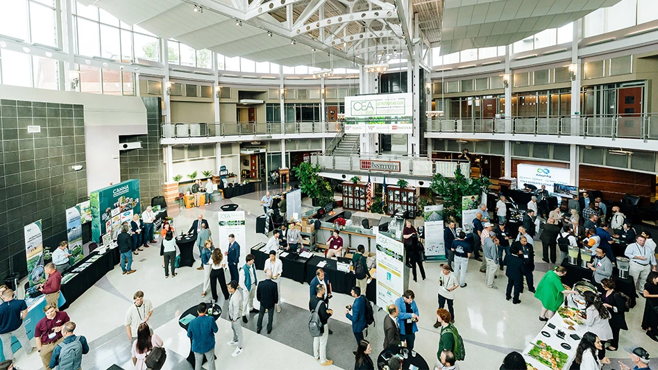 An overhead photo of a circular room filled with people and educational booths at a conference.