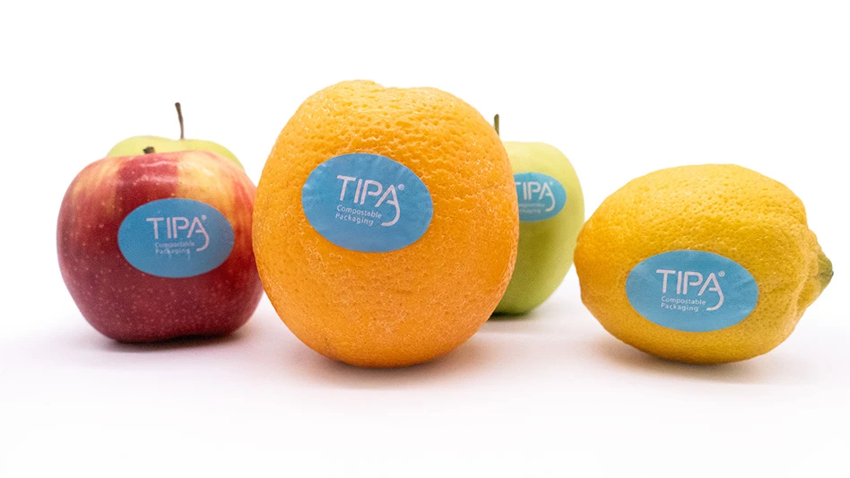 A red apple, orange, green apple and yellow lemon, all with blue stickers reading TIPA Compostable Packaging in white text.