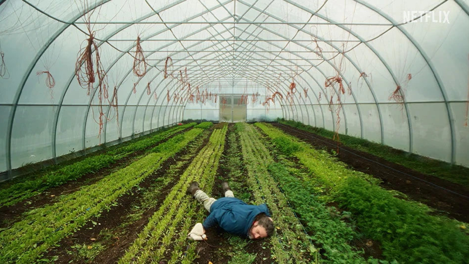 A man laying in a greenhouse